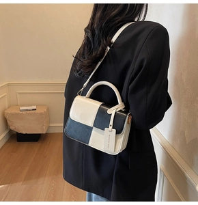 Model wearing a modern black and white contrast color handbag with a minimalist suit
