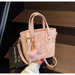 Détail du sac seau rose en similicuir avec motifs papillons et breloque en forme d'os
