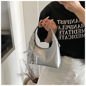 Détail du sac hobo argenté avec un nœud bleu et des breloques en perles
