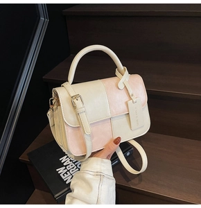Detail of color-block PU leather bag with top handle, adjustable strap, and hanging tag