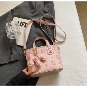 Pink bucket bag with embossed star patterns and cute puppy charm in a lifestyle setting