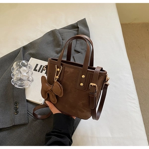 Détail d'un sac seau en cuir marron avec gaufrage rétro et un joli pendentif en forme d'ours
