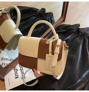 Close-up of contrast color handbag with adjustable strap and designer brand tag