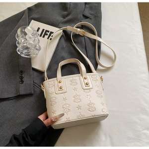 Detail view of off-white lychee leather bucket bag with star embossed pattern and rivets
