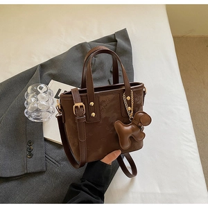 Sac seau marron foncé avec gaufrage et breloque chiot sur une veste de costume grise