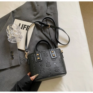 Detail of black bucket bag featuring intricate floral embossing and gold hardware