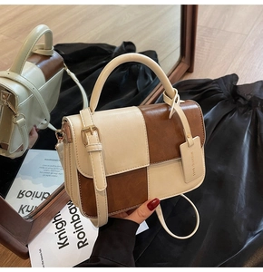 Detail view of contrast leather handbag with adjustable strap and vintage gold buckle