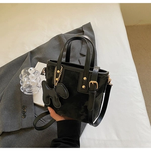 Détail d'un sac cabas noir en PU avec breloque chien et boucles métalliques dorées
