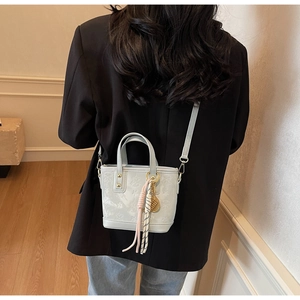 Vista dettagliata di una borsa a secchiello azzurra con stelle a rilievo e ciondoli su modella