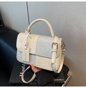 Detail of minimalist beige and grey PU leather bag with gold buckle and top handle