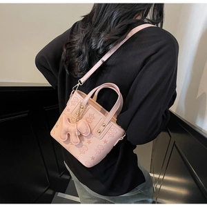 Detail of pink embossed bucket bag with star patterns and a plush charm on a shoulder strap