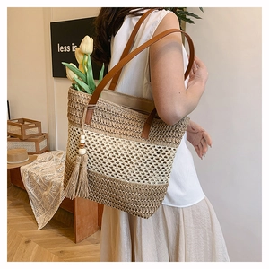 Detail of large woven beach tote with brown leather straps and wooden bead tassel decor