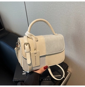 Detail view of contrast color handbag featuring beige and light blue faux leather texture