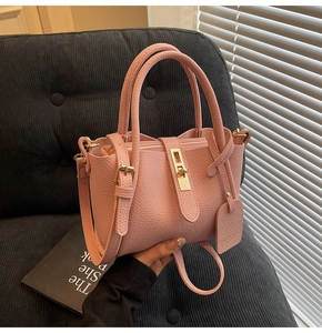 Detailed view of pink lychee grain leather tote bag with gold hardware and shoulder strap