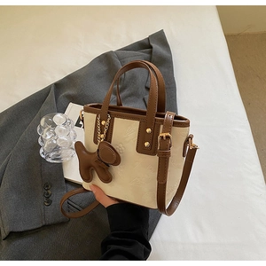 Détail du sac cabas bicolore avec motifs floraux en relief et charm chien marron