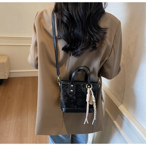 Vista posteriore di una modella con mini borsa in pelle nera goffrata a stelle e nastro a righe