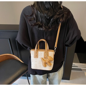 Detail of two-tone bucket bag with star embossing and a cute leather bear charm
