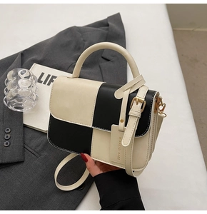 Detail of color block handbag showing black and cream checkers with gold hardware