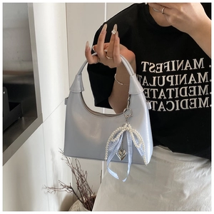 Detail of light blue hobo bag with pearl charm and blue checkered ribbon accessory