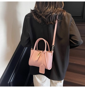 Detail of pink pebbled leather handbag with gold metal lock and elegant top handles