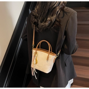 Detail der minimalistischen cremefarbenen Beuteltasche mit braunem Rand am Modell