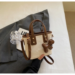 Détail du sac seau contrasté avec motifs d'ours gaufrés et breloque en cuir élégante