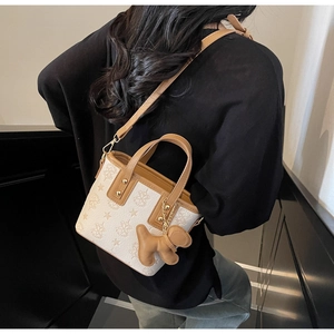 Detail of cream bucket bag with embossed star patterns and cute gingerbread man charm