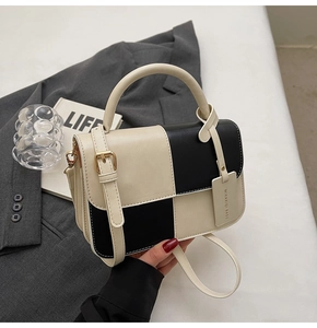 Detailed close-up of a two-tone crossbody bag featuring a gold buckle and brand tag