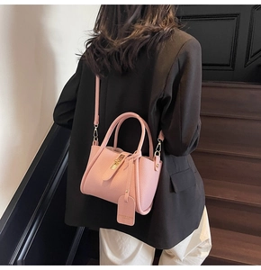 Detail of pink lychee leather handbag with golden lock and adjustable shoulder strap