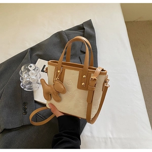 Détail du sac seau en cuir gaufré crème avec anses marron et breloque chiot