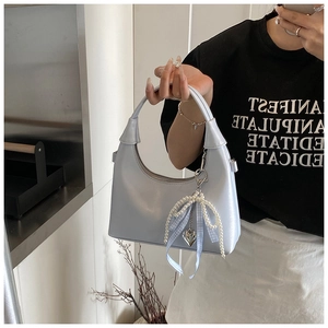 Détail du sac hobo bleu clair avec breloque nœud en perles et ruban à carreaux