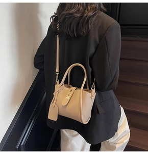 Detail of beige lychee pattern bucket bag with gold buckle on a crossbody model
