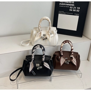Trio di borse in pelle bianca, nera e marrone con manici avvolti in seta e chiusure in metallo