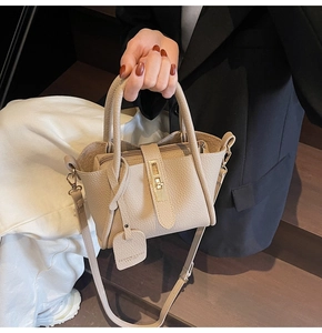 Detailed close-up of apricot lychee pattern leather handbag with metal buckle and top handle