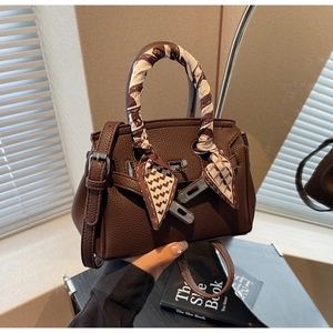 Dettaglio borsa in pelle marrone a grana litchi con fibbia argento e foulard in seta