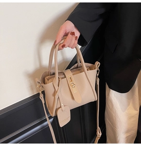 Detail of beige lychee textured bucket bag with golden twist lock and adjustable strap