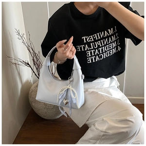 Détail du sac hobo argenté brillant avec bandoulière en perles et breloque cœur en métal