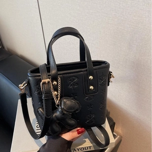 Schwarze Beuteltasche mit Sternprägung, goldenen Beschlägen und Hundeanhänger