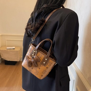 Braune Beuteltasche mit Sternmuster, goldener Hardware und süßem Welpenanhänger