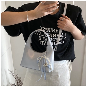 Détail du sac croissant bleu pastel avec nœud en perles et pendentif cœur argenté