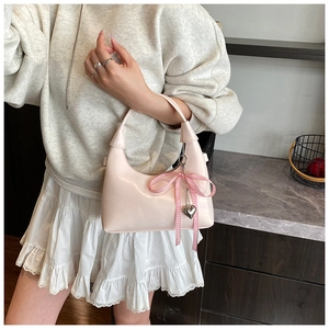 Détail du sac hobo rose brillant avec nœud à carreaux et pendentif en forme de cœur argent