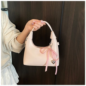 Détail du sac hobo rose clair avec fini perlé, nœud rose et pendentif cœur argenté