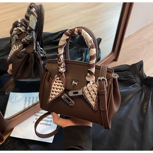 Dettaglio borsa a mano in pelle martellata marrone scuro con chiusura argento e foulard