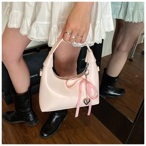 Détail du sac hobo rose brillant avec nœud à carreaux et pendentif cœur argenté