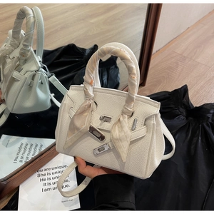 Dettaglio borsa a mano in pelle bianca con foulard in seta floreale sul manico