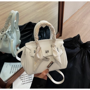 Dettaglio della borsa a mano bianca in pelle martellata con chiusura argento e foulard