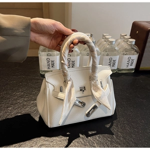 Dettaglio di borsa bianca in pelle martellata con foulard di seta floreale sul manico