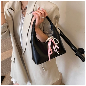 Détail du sac à main noir en demi-lune avec perles blanches et ruban à carreaux rose