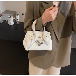 Dettaglio borsa a mano in pelle bianca con foulard decorativo e chiusura in argento