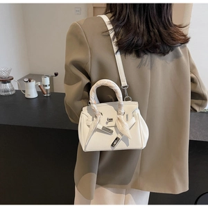 Dettaglio borsa a mano bianca in pelle con foulard decorativo sul manico e chiusura in metallo